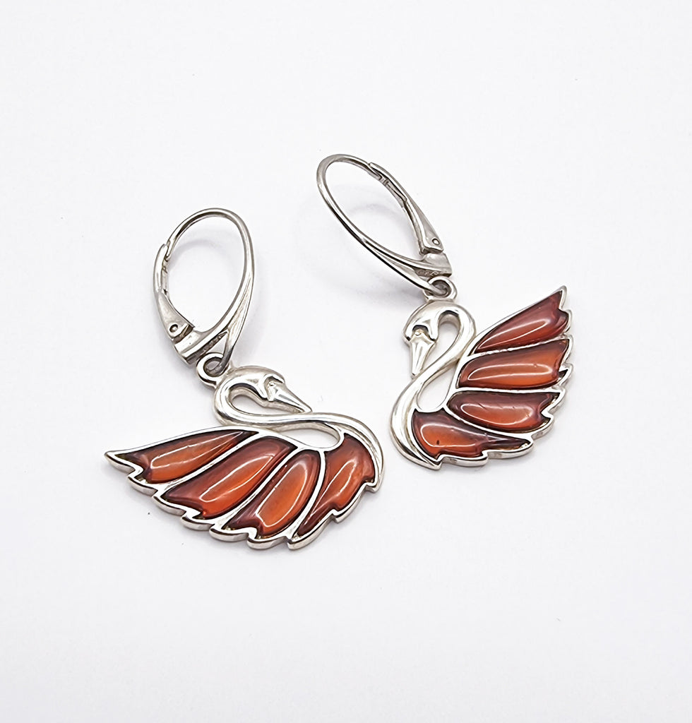 Elegant swan drop earrings in sterling silver, featuring genuine cognac Baltic amber and secure French hooks for a timeless, refined look. Origin Poland