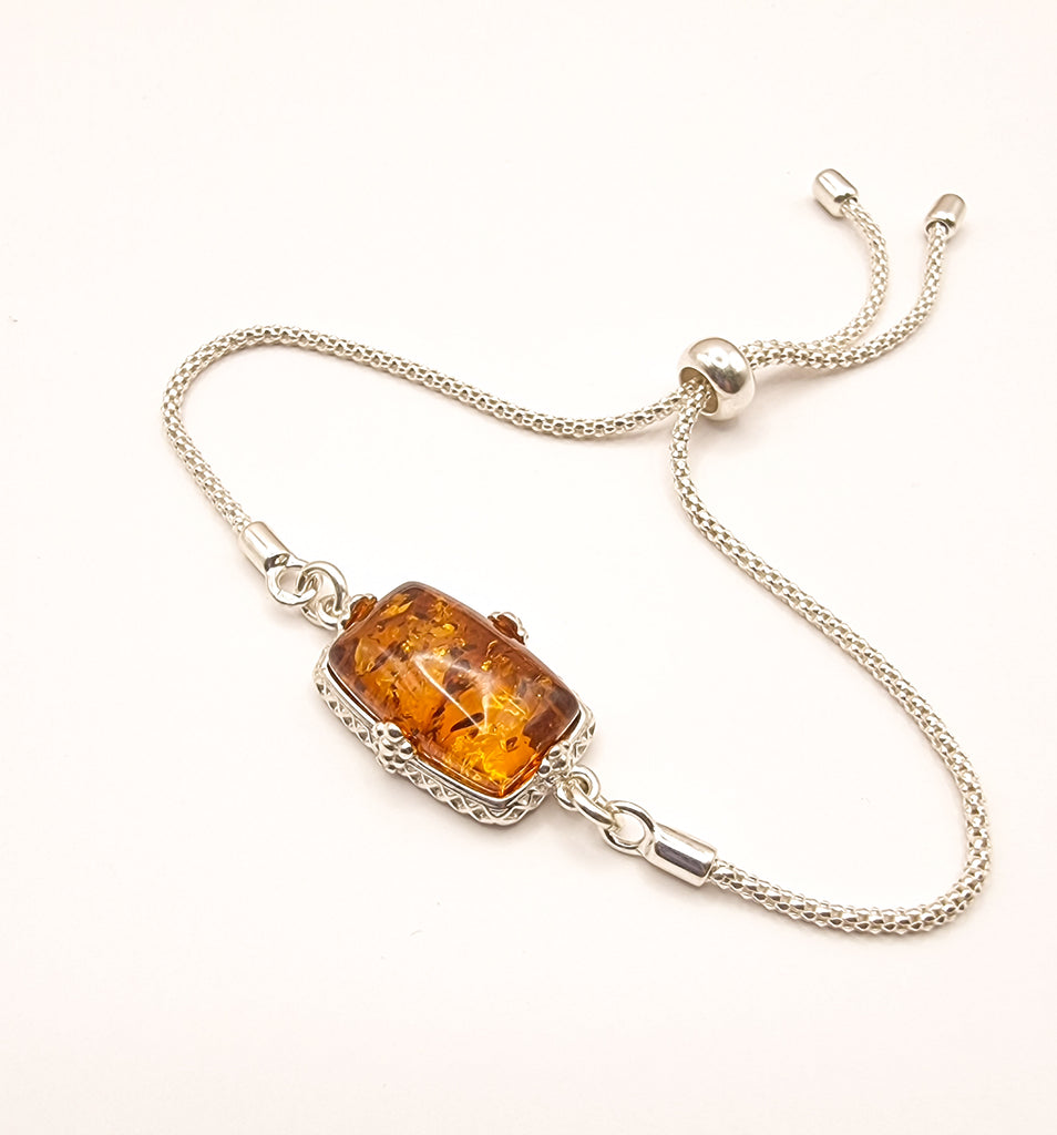 Elegant lariat-style bracelet crafted from sterling silver, featuring gorgeous natural Baltic amber in a rich cognac hue. A sophisticated blend of timeless charm and modern design.