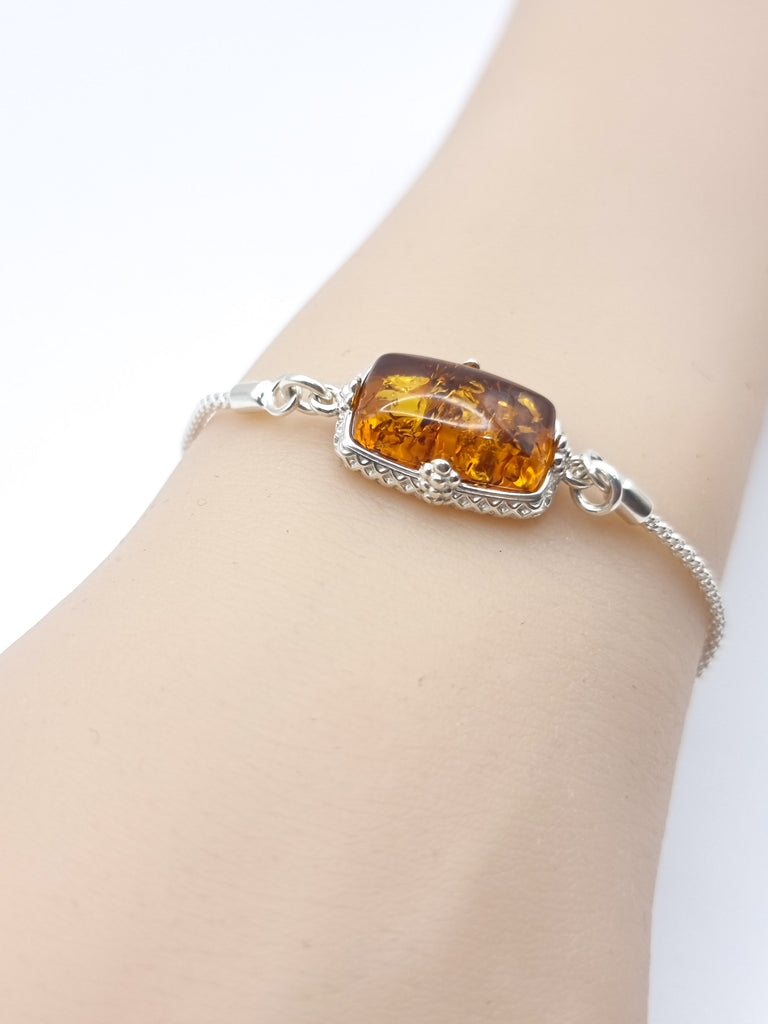 Elegant lariat-style bracelet crafted from sterling silver, featuring gorgeous natural Baltic amber in a rich cognac hue. A sophisticated blend of timeless charm and modern design.