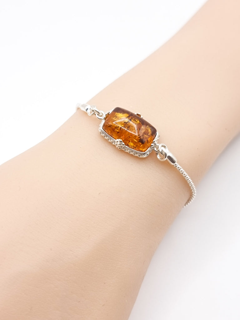 Elegant lariat-style bracelet crafted from sterling silver, featuring gorgeous natural Baltic amber in a rich cognac hue. A sophisticated blend of timeless charm and modern design.