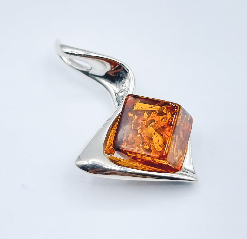 A large cube shaped natural cognac Baltic Amber pendant on Sterling Silver swirl ribbon