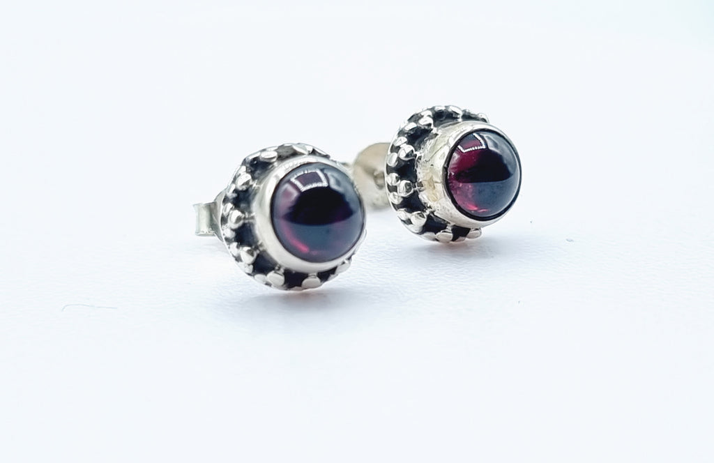 A tiny ear stud set with beautiful Garnet cabochon on sterling silver with decorative beaded frame. Origin India