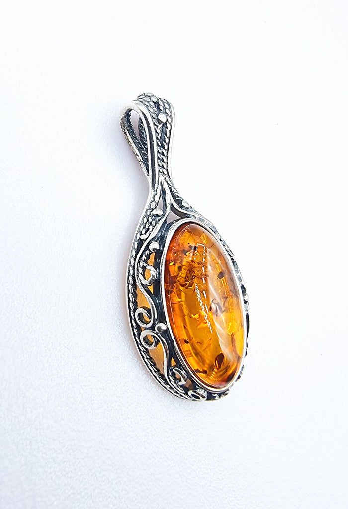 Classy sophisticated natural Baltic Amber pendant in Cognac tone, set on decorative swirl Sterling Silver bezel