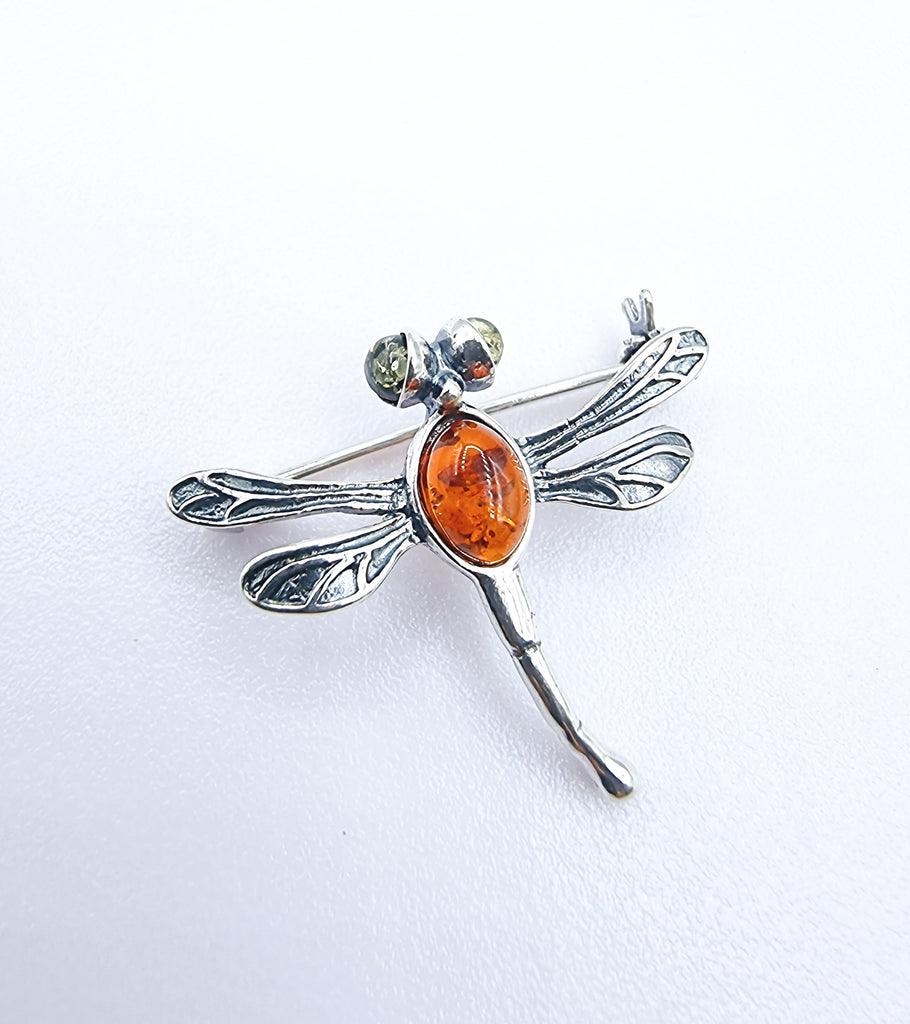 A tiny dragonfly Brooch, crafted with natural Baltic Amber on Sterling Silver. The body of the dragonfly is set with cognac Amber and the eyes are in green. 