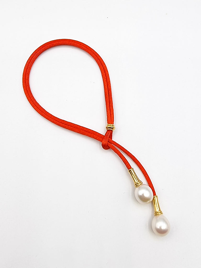 Adjustable bracelet on red silk cord with lustrous cultured white Freshwater Pearl drops, on gold plated stainless steel.