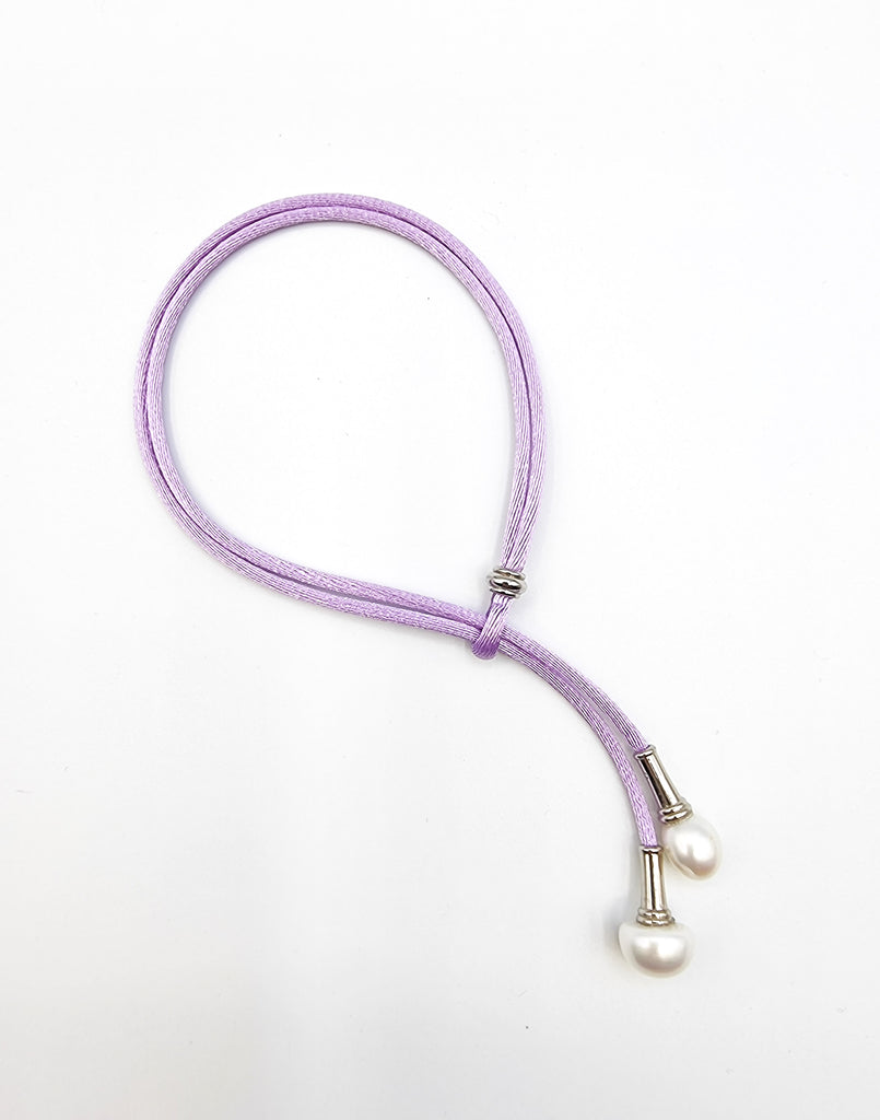 Adjustable bracelet on mauve silk cord with lustrous cultured white Freshwater Pearl drops, on gold plated stainless steel.