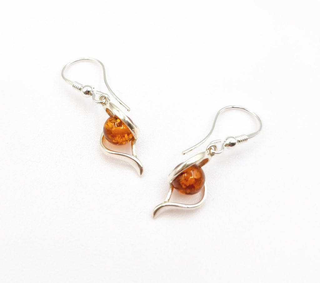 An elegant pair of dangling earrings crafted with natural cognac Baltic Amber, set on an intricately designed 925 Sterling Silver swirl pattern. One of a kind design. Will look beautiful with any outfit. Origin Poland