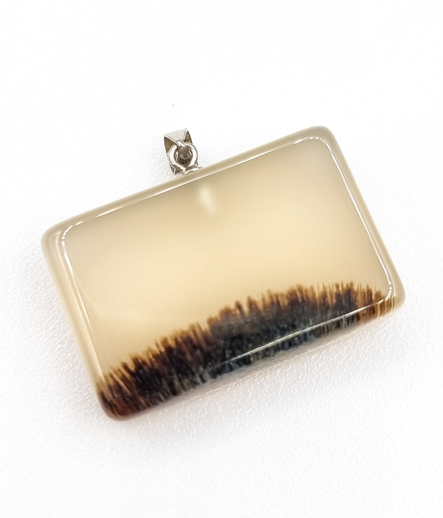 A beautiful, classy rectangular natural Dendritic Landscape Agate pendant, featuring a serene river bed bush. Attached with a 925 Sterling Silver bail, it adds a touch of elegance to this pendant. 