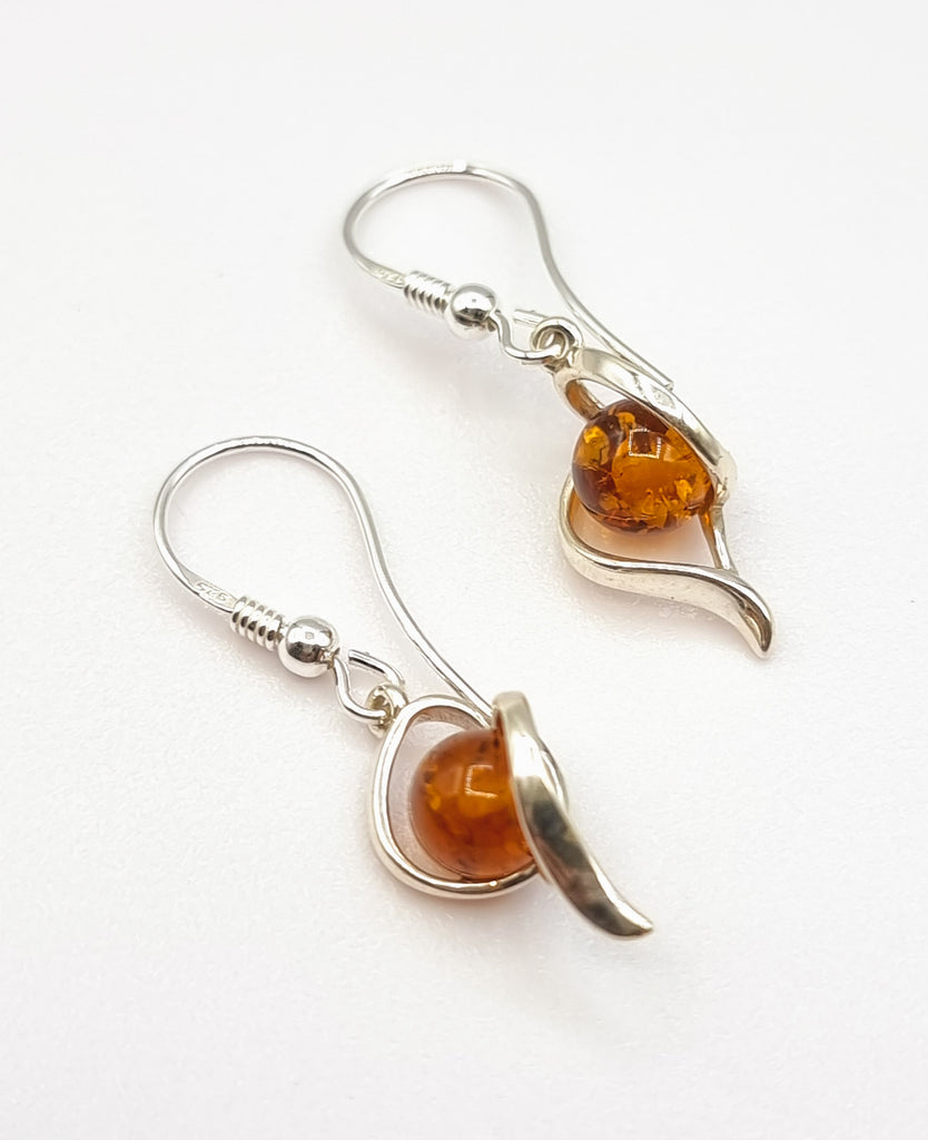 An elegant pair of dangling earrings crafted with natural cognac Baltic Amber, set on an intricately designed 925 Sterling Silver swirl pattern. One of a kind design. Will look beautiful with any outfit. Origin Poland