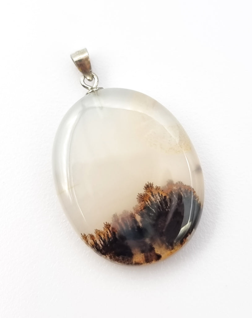 A beautiful oval shaped natural dendritic landscape agate pendant, featuring an attractive forest like inclusion. Set with a simple 925 sterling silver bail, this pendant is sure give a sense of calmness to nature lovers