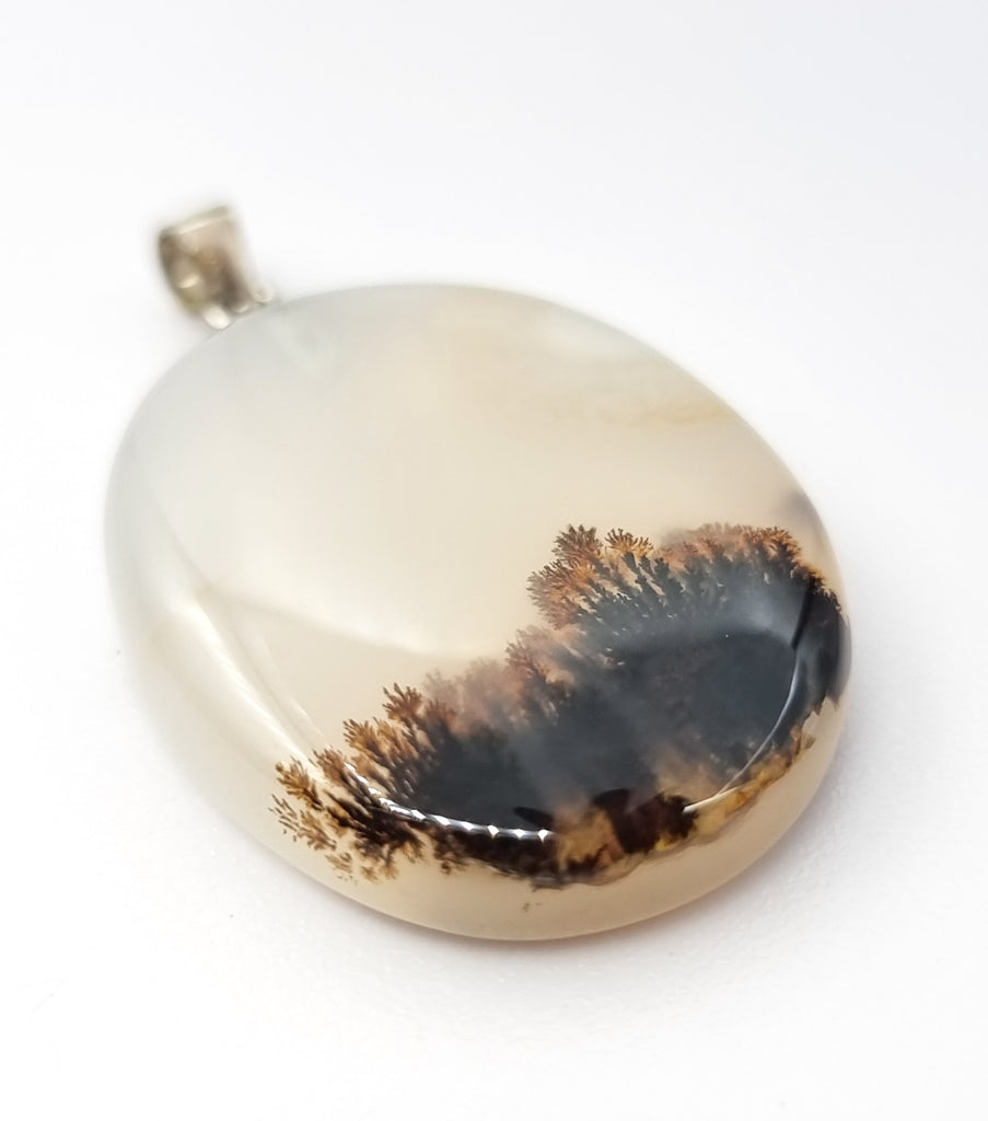 A beautiful oval shaped natural dendritic landscape agate pendant, featuring an attractive forest like inclusion. Set with a simple 925 sterling silver bail, this pendant is sure give a sense of calmness to nature lovers