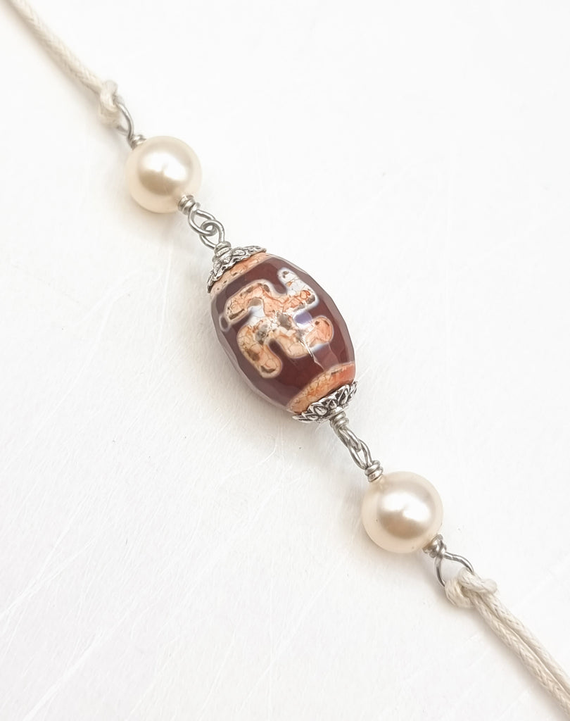 A handmade Rakhi delicately crafted with gorgeous ‘Swastika’ Dzi Agate, symbolising positivity and protective energy, and lustrous imitation pearls. Truly unique and one-of-a-kind!