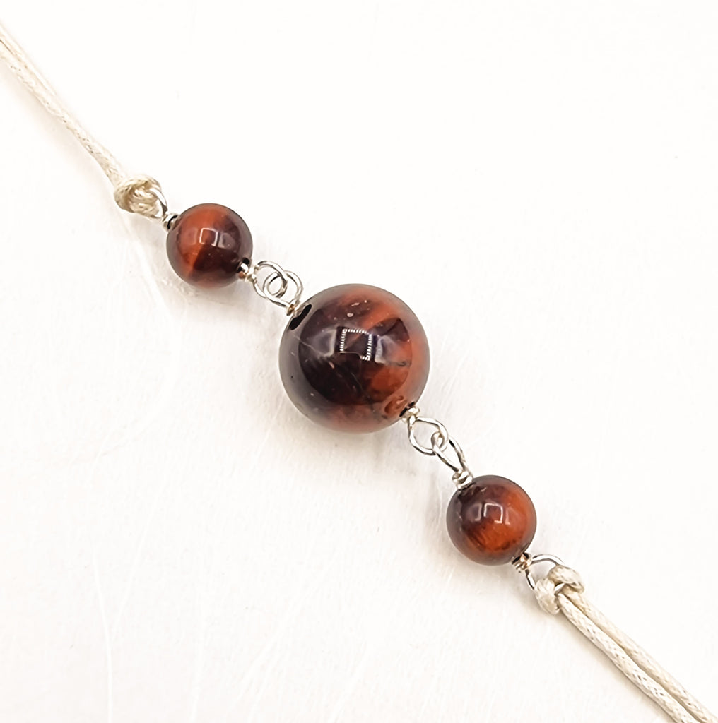 A handmade Rakhi delicately crafted and embellished with natural Red Tiger Eye gemstones. This elegant and traditional combination adds a touch of love and positive energy in the special sibling bond. Truly unique and one-of-a-kind!