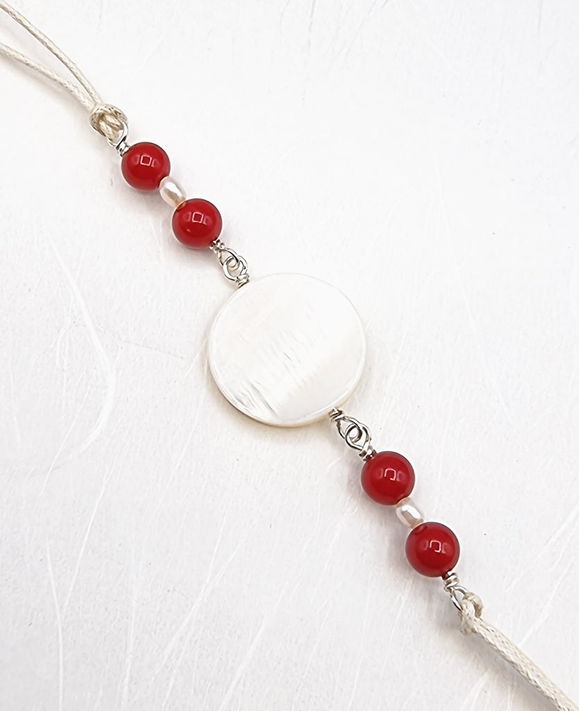 A handmade Rakhi delicately crafted with a gorgeous Mother of Pearl Shell accent and vibrant red synthetic Bamboo Corals. This elegant and sophisticated design adds a touch of love and purity in the special sibling bond. Truly unique and one-of-a-kind!