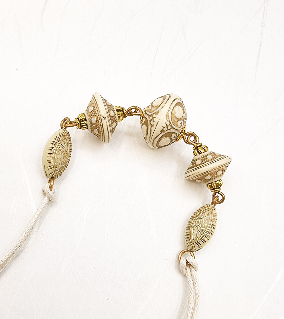 A handmade Rakhi delicately crafted with gold carved acrylic beads in a soothing cream tone. This elegant and traditional combination adds a touch of love and purity in the special sibling bond. Truly unique and one-of-a-kind!