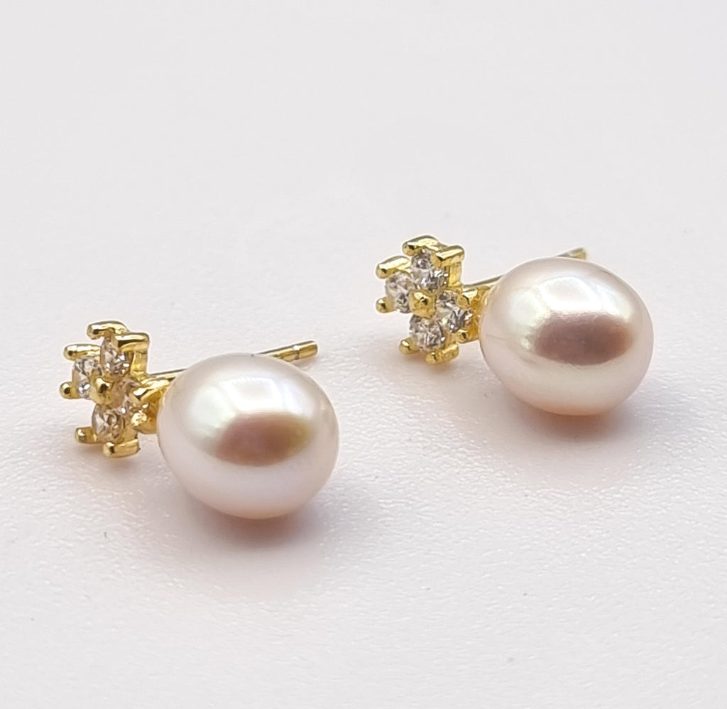 Elevate elegance with these gorgeous Freshwater pearl drop stud earrings. Handpicked for their lustrous white hue with a pink overtone, these beautiful Freshwater pearls are designed on lovely gold-plated sterling silver floral studs, adorned with cubic zirconia, that brings sophistication to any occasion – perfect for mornings or evenings.