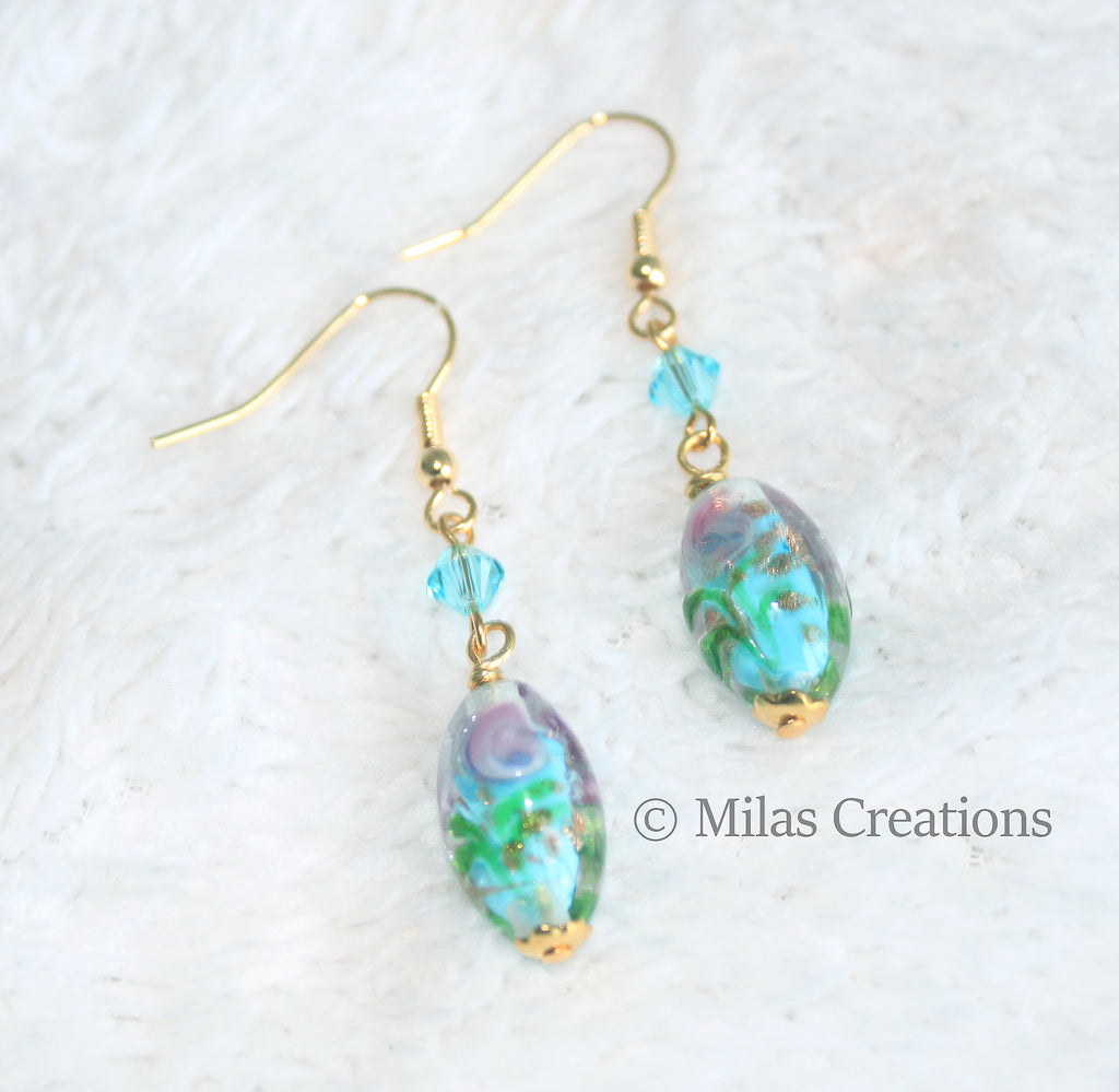 A pair of beautiful hand blown glass bead dangling earrings in light blue, combined with light blue imitation crystals, with gold-plated earring hooks