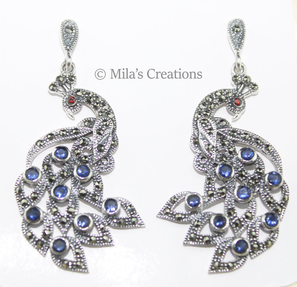 A gorgeous pair of peacock earrings on Sterling Silver encrusted with Sapphires depicting the beautiful feathers and tiny little Rubies highlighting the eyes of this majestic bird.