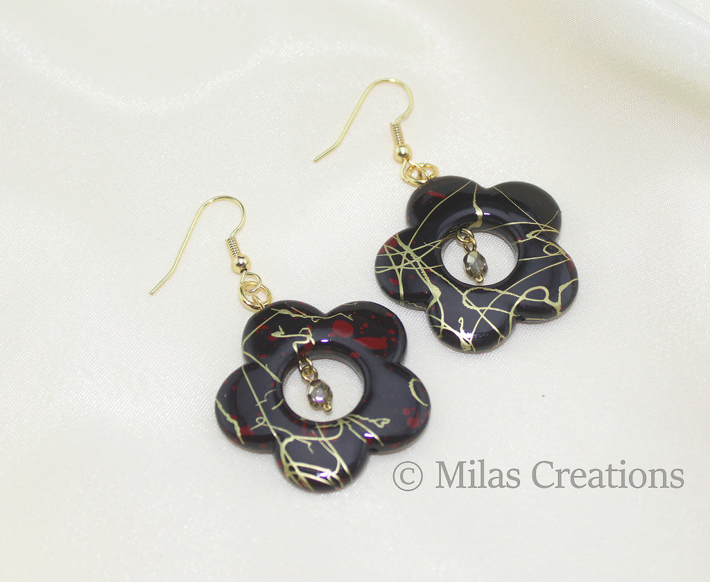 A pair of handmade earrings designed with black acrylic flowers and Preciosa crystals