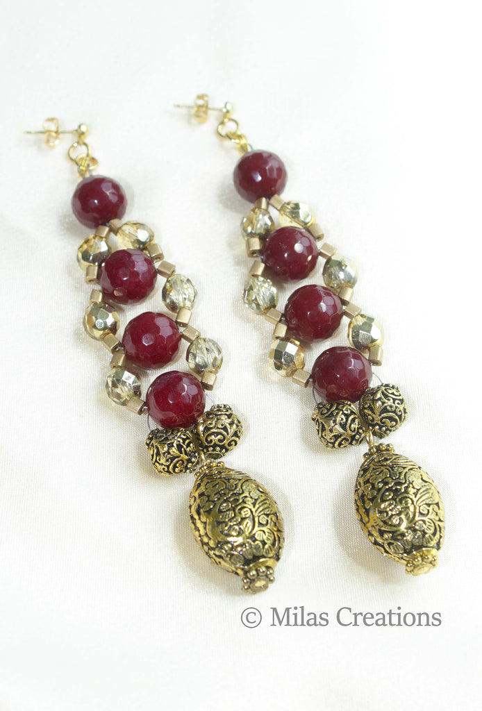 A pair of hand woven earrings designed with an array of beautiful deep red dyed Chalcedony, metallic wooden beads and Preciosa crystals with carved antique gold plated accent bead