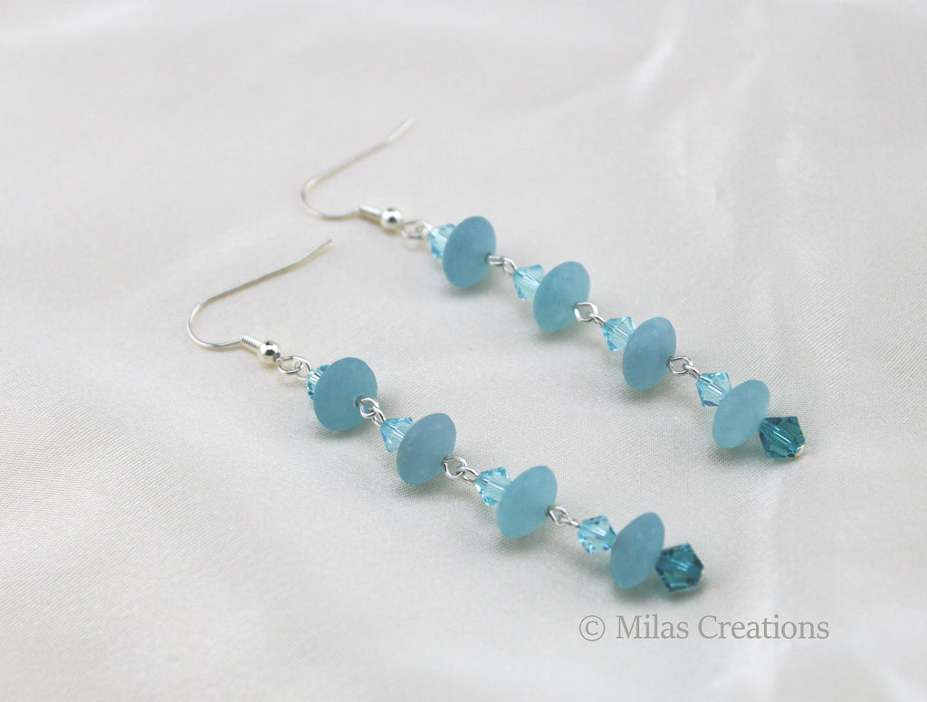 A pair of handmade earrings in light blue Aqua Quartz combined with imitation crystals. 